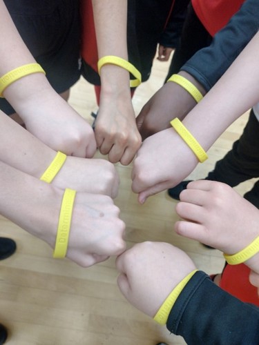 hands coming together, showing yellow wristbands